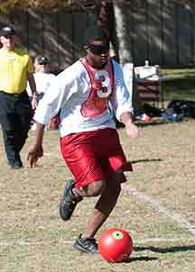 Player with a number three jersey kicks a red kickball.